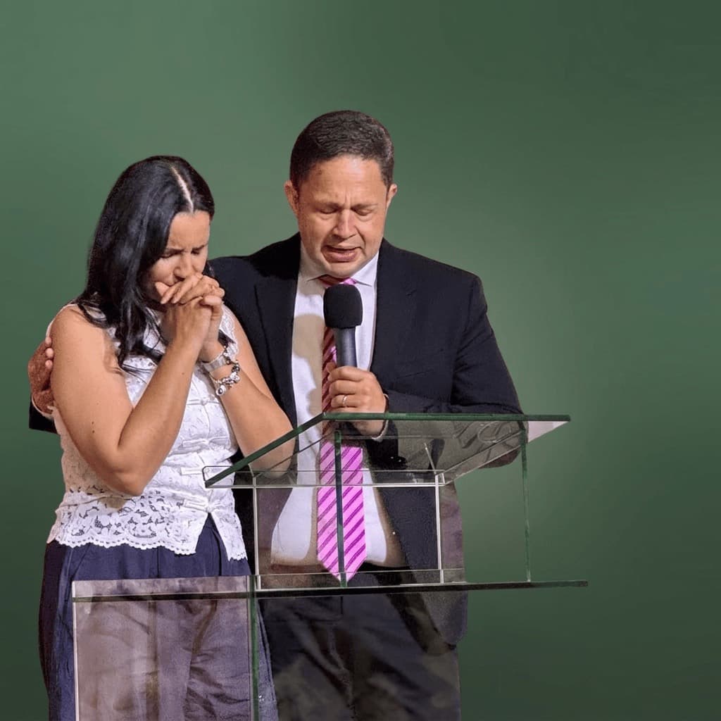 El pastor y la pastora orando juntos ante el púlpito